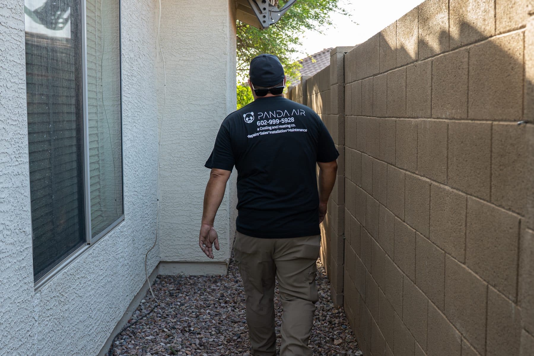 Panda Air technician walking to the unit at the side of a house